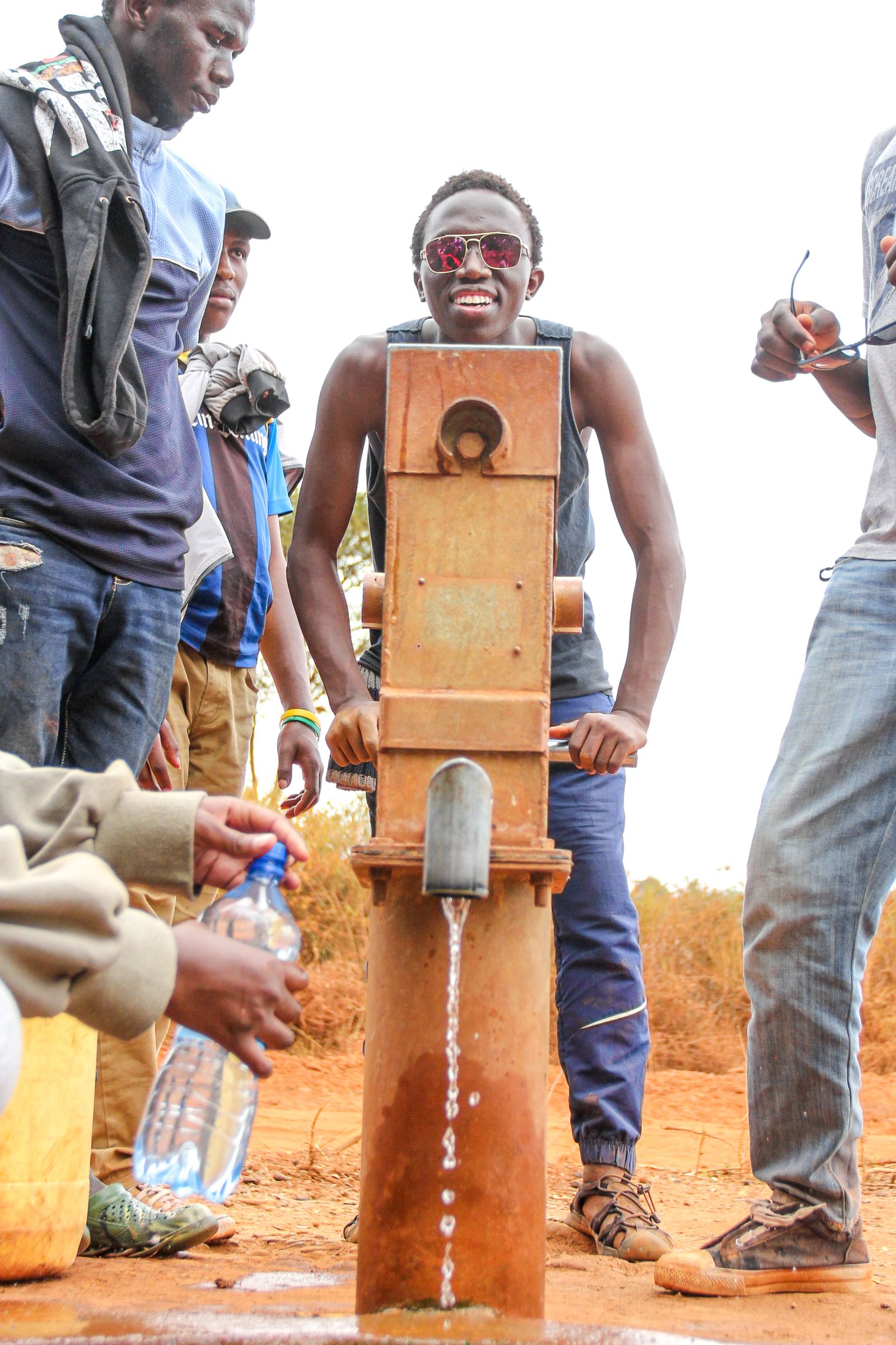 People gathered around a borehole hand pump