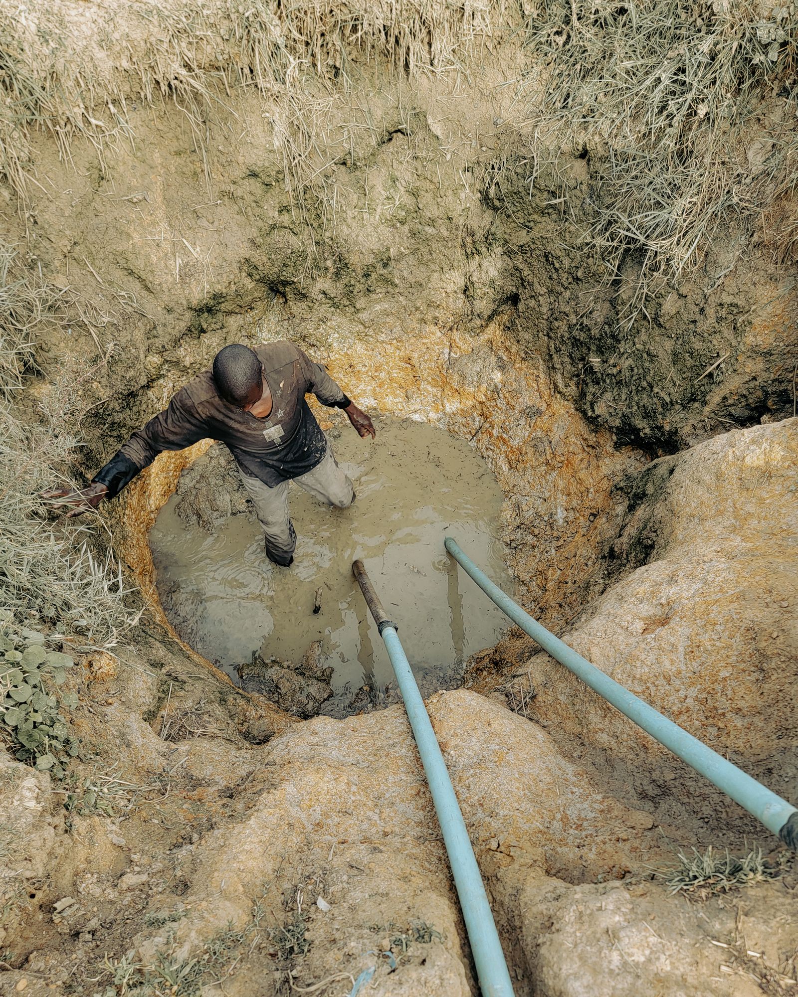 A technician working on borehole pipework in the ground