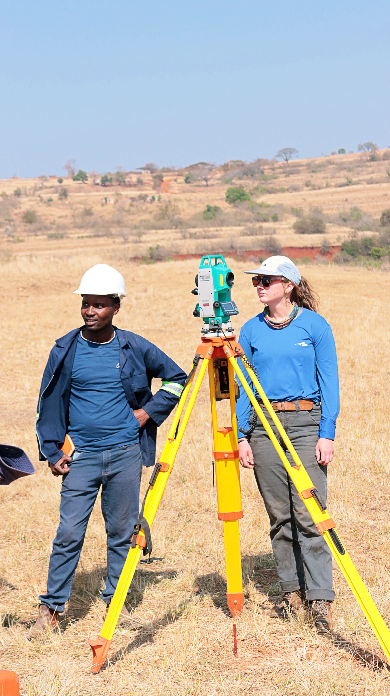 A survey team setting up equipment on open grassland