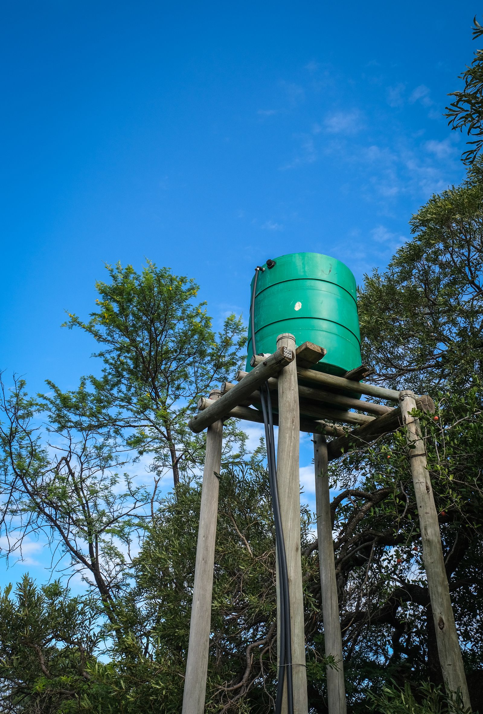 A green water tank on a raised stand
